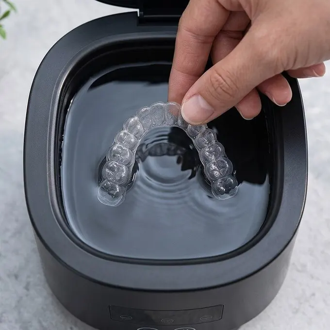 A clear retainer set on the bottom of the DentaSonic tank